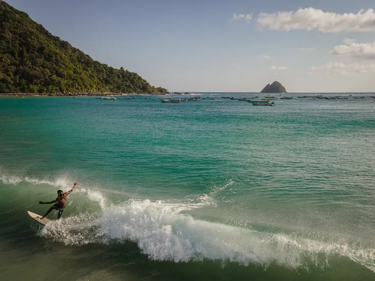Surfer riding a wave on Selong Beach